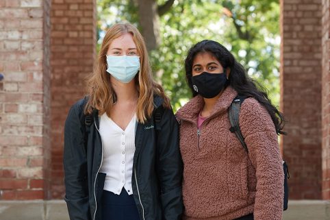 Two students standing outside Baldwin Hall wearing masks.